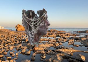 Screen capture of AR sculpture against a rocky shore